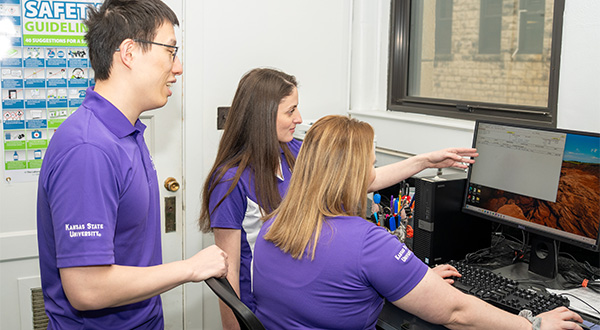 students and professor looking at computer